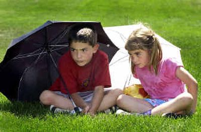 
With umbrellas giving them shade from the intense afternoon sun, siblings, Troy , 8, and Kiana Verplancke, 7, watch their sister, Krizia, 12, play her U-12 soccer match at Plantes Ferry Soccer Complex Monday. The Verplancke's are from Laramie, Wyoming and are part of the thousands of players and spectators in town for the Far West Regional Soccer Championships this week. 
 (Colin Mulvany / The Spokesman-Review)