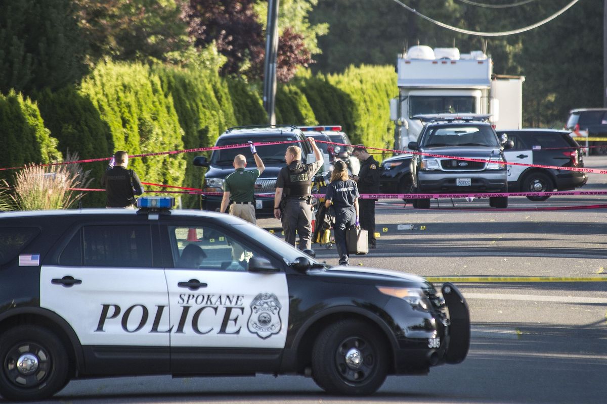 Law enforcement investigators walk under the crime-scene tape on the 5900-block of South Mount Vernon Street in Spokane, after a man was shot and killed Monday, July 3, 2017, by police officers responding to a domestic violence call. (Dan Pelle / The Spokesman-Review)