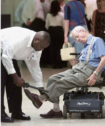 
Federal screener Lionel Phillips, left, checks the shoes of an unidentified passenger at Dallas Love Field airport in Dallas. Some private security firms have begun pitching themselves as a class above the old guard of airport screening companies that were ridiculed after the 2001 terrorist attacks.
 (File/Associated Press / The Spokesman-Review)