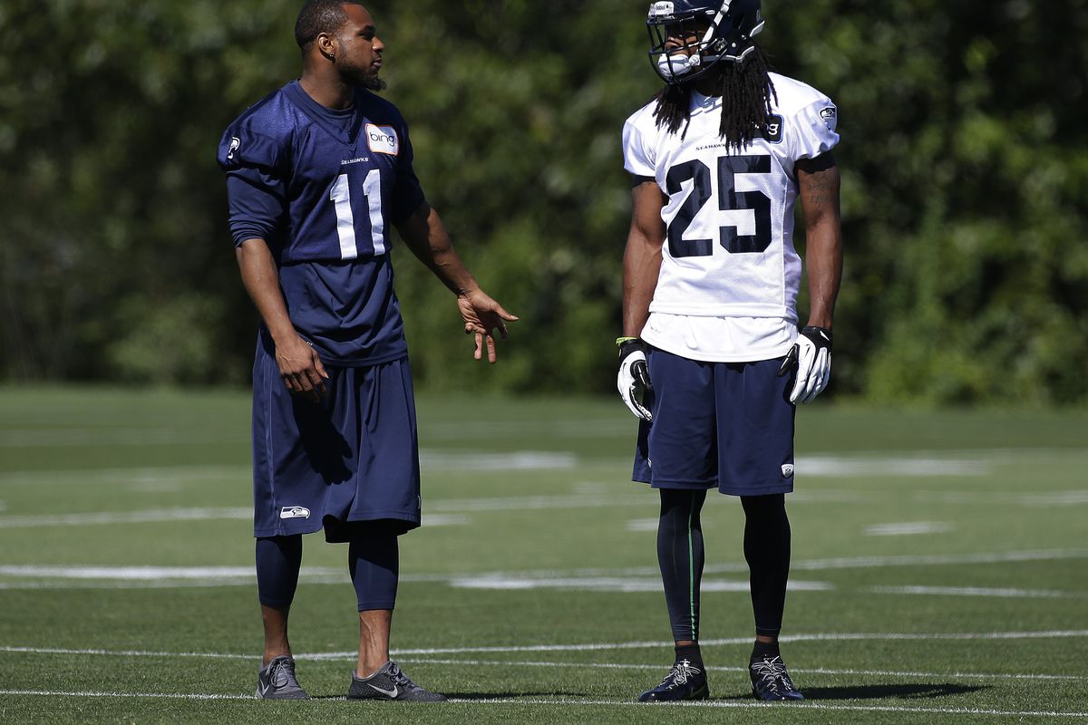 Percy Harvin (11) talks with teammate Richard Sherman at training camp Thursday. Harvin is on the physically-unable-to-perform list. (Associated Press)