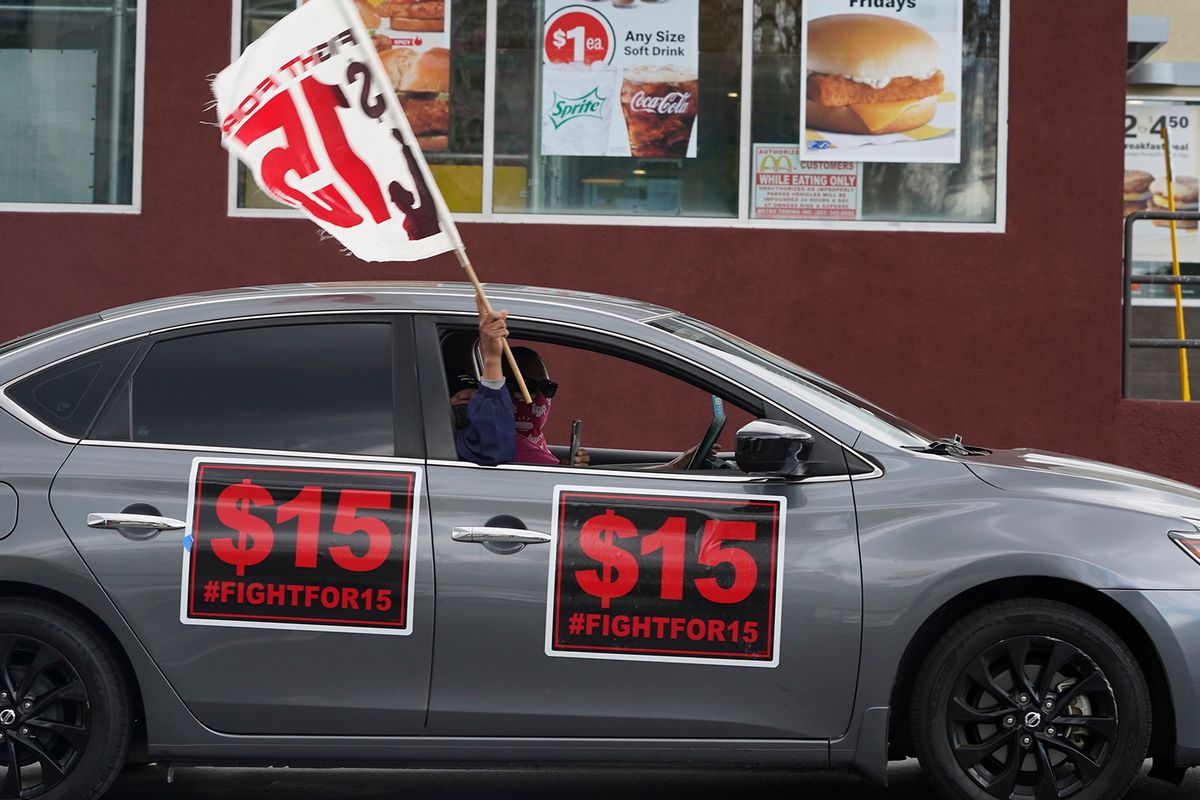 FILE - Fast-food workers drive though a McDonald