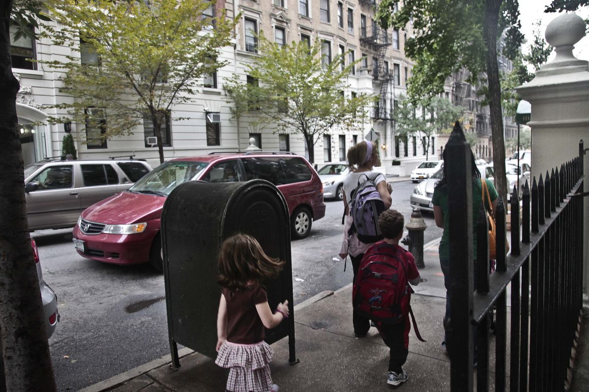 Youngsters walk with their escorts across the street from a shelter on 95th Street on Wednesday, Oct. 3, 2012 in New York.  Neighborhood residents are in turmoil, saying they were blindsided by the suddenness of the shelter