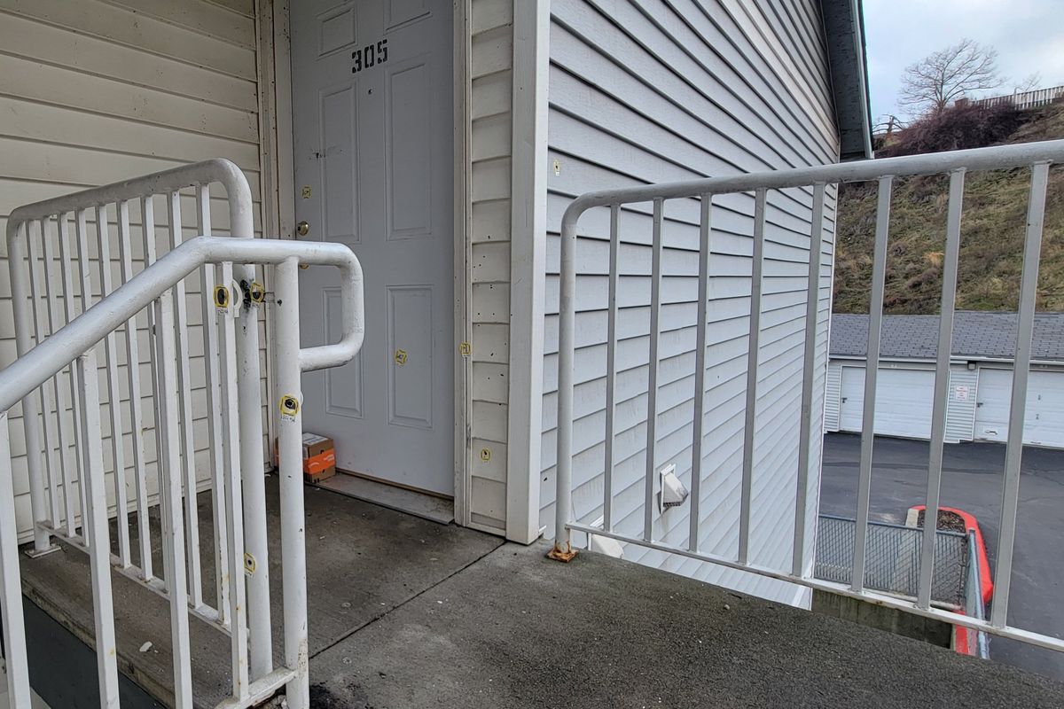 Yellow evidence markers circle the bullet holes littering the railing, door and landing of the third story apartment at the Northcliff Terrace Apartments complex where the Spokane Police Department shot and killed a man Sunday evening, pictured here on Dec. 30.  (Nick Gibson / The Spokesman-Review)