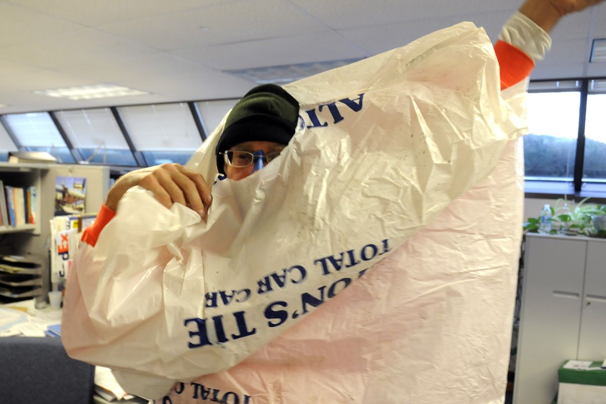 Sherwood pulls on an old tire bag, which serves as his rain gear, before his ride home. Because of the mild weather, it turned out that he didn’t need the bag Tuesday. When the weather is too harsh for his makeshift rain gear, Sherwood said he takes the bus. (Jesse Tinsley / The Spokesman-Review)