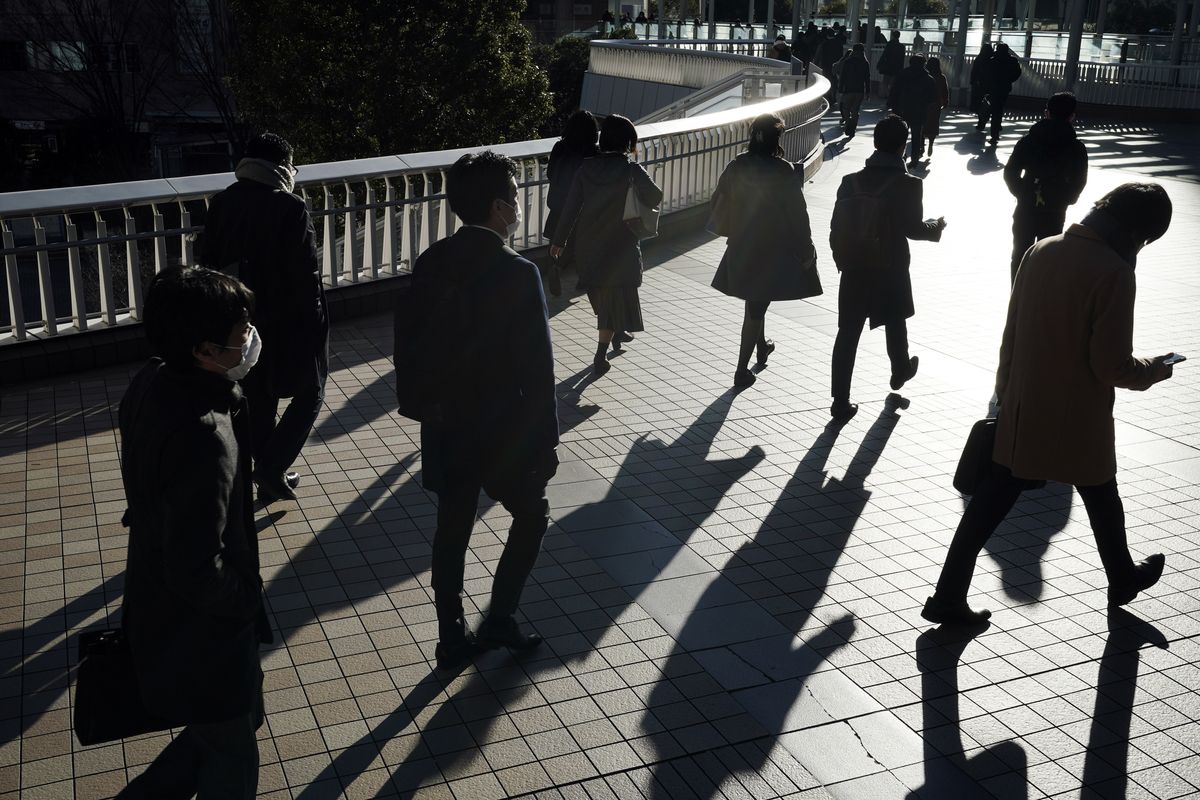 Commuters wearing face mask make their way during a rush hour Friday, Jan. 8, 2021 in Tokyo. Japanese Prime Minister Yoshihide Suga declared a state of emergency Thursday for Tokyo and three other prefectures to ramp up defenses against the spread of the coronavirus.  (Eugene Hoshiko)