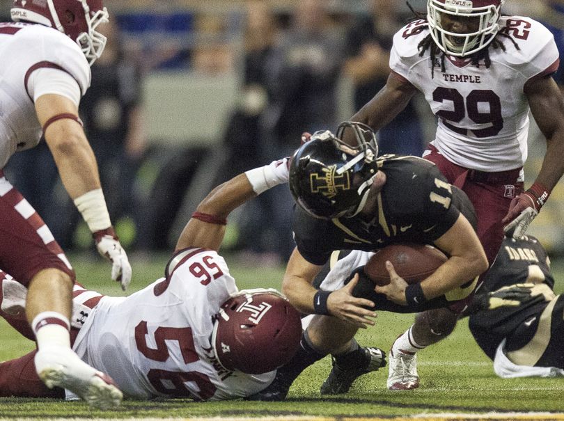 Idaho QB Chad Chalich gets his helmet spun around as he’s brought down by Temple’s Sharif Finch in the second quarter. (Associated Press)