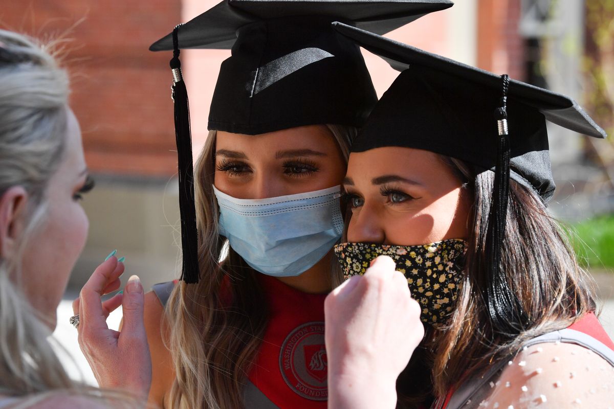 Brittney Kluse, a Tri Cities based photographer, adjusts facemasks on Mackenzie Monson, left, and Natalie Przybylski, best friends and soon-to-graduate WSU seniors before they posed senior portraits on Thursday, April 15, 2021, on WSU's campus in Pullman, Wash. Both women lamented not being able to walk at graduation due to Covid-19 regulations.  (Tyler Tjomsland/The Spokesman-Review)