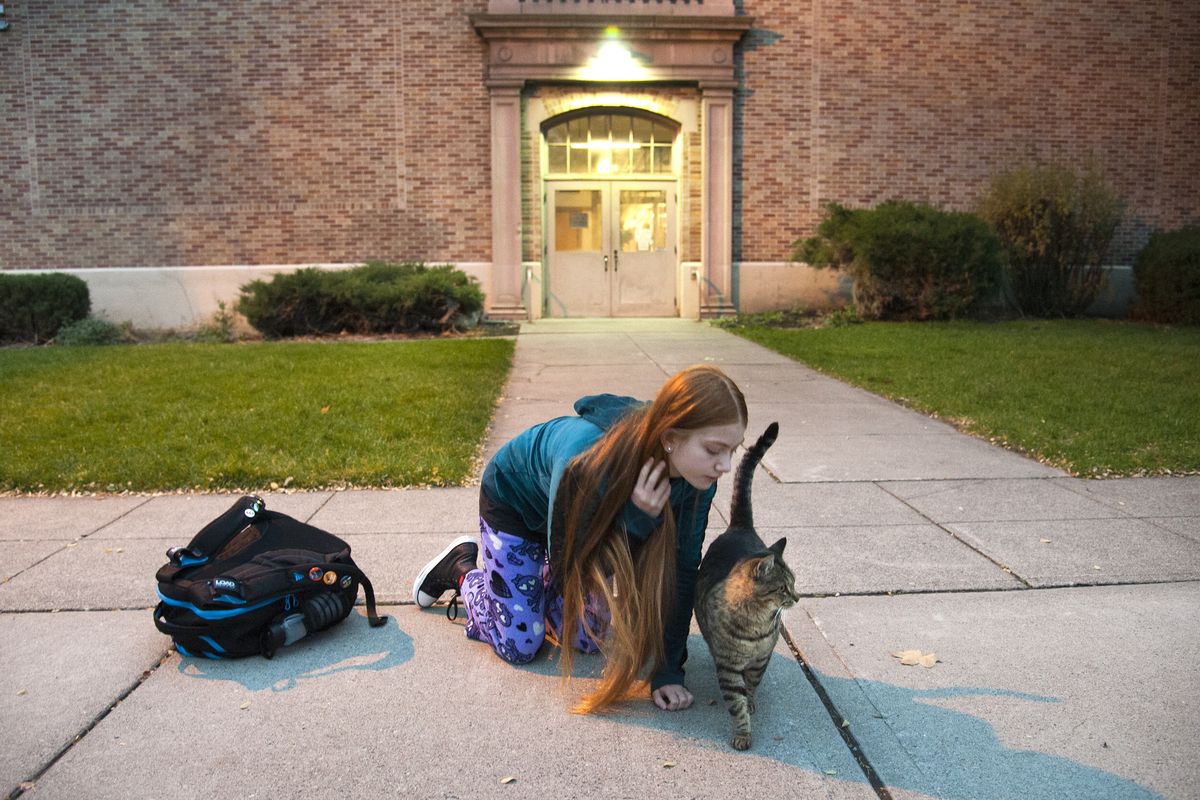Libby Center student Ella Fornof spends a few moments early Friday morning with the neighborhood cat. Libby greets the schoolchildren when they arrive in the morning and depart in the afternoon. (PHOTOS BY DAN PELLE)