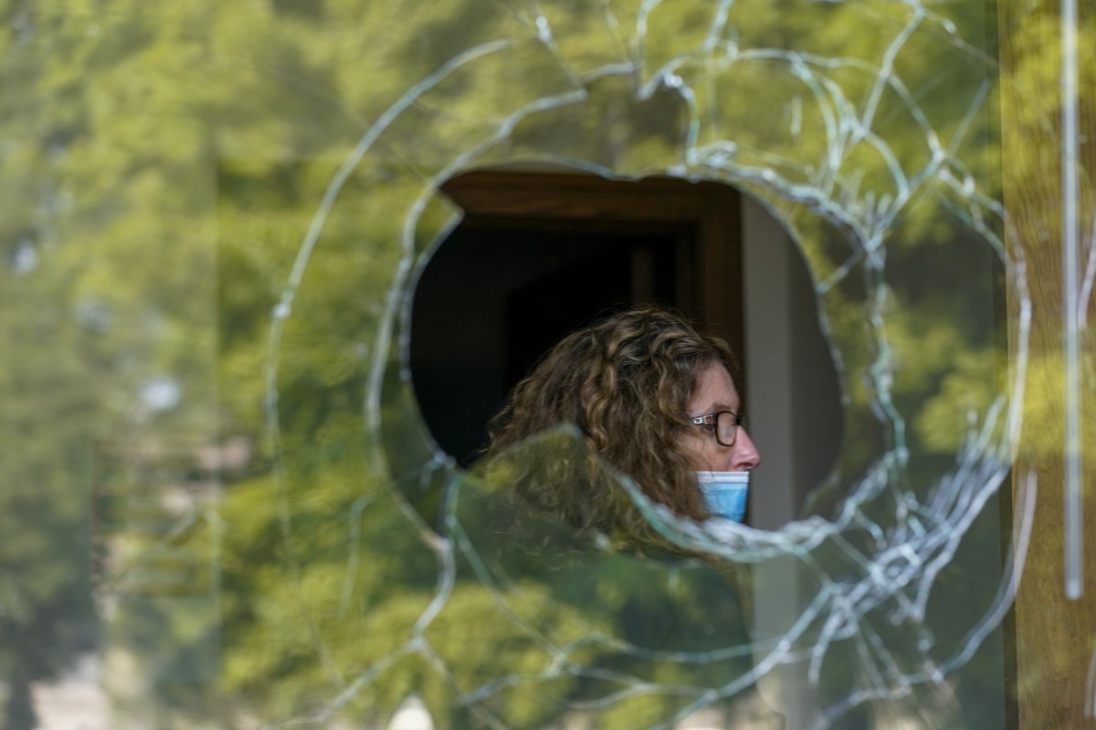 A woman is seen through a broken window at the Harborside Academy Monday, Aug. 24, 2020, in Kenosha, Wis. The windows were broken after protests broke out late Sunday night following a police shooting.  (Morry Gash)