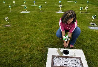 
Deanna Henderson decorates the grave of her granddaughter and 90 other infant graves with pinwheels in one of four separate areas known as 