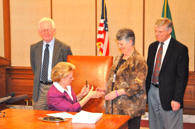 Gov. Chris Gregoire congratulates House Budget Chairwoman Kelli Linville, D-Bellingham, and offers her the pen after signing the 2010 supplemental budget on May 4, 2010. (Jim Camden/Spokesman-Review)