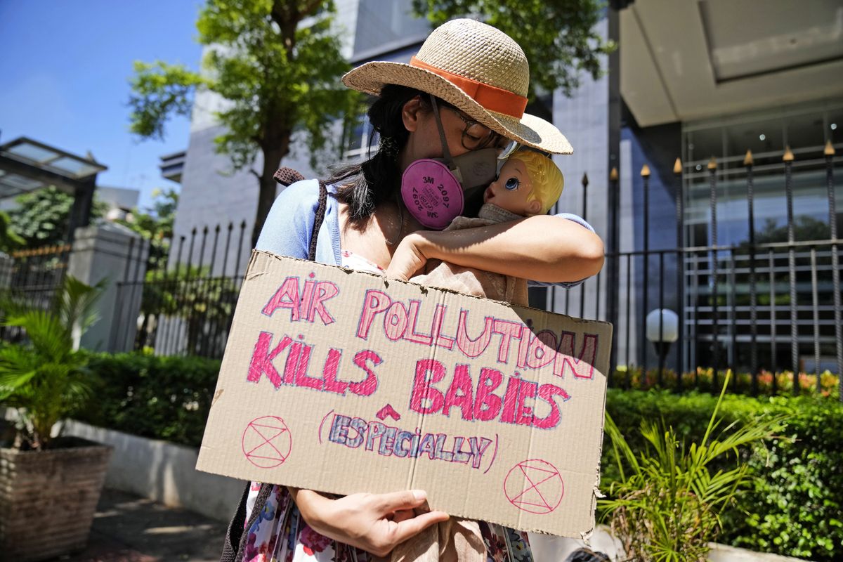 An activist displays a placard with a doll representing babies affected by air pollution during a protest outside Central Jakarta District Court where judges are scheduled to announce their verdict on a civil lawsuit filed against several Indonesian officials, including President Joko Widodo and Jakarta Governor Anies Baswedan, for their failure to improve poor air quality in the capital city, in Jakarta, Indonesia, Thursday, Sept. 16, 2021.  (Dita Alangkara)