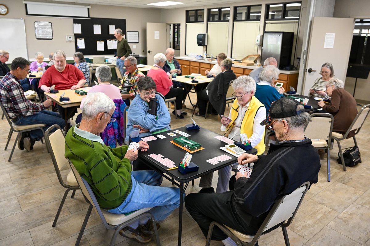 In the foreground, from left, Jim Williams, Jeanne Moore, Catherine Geraghty and Peter Barthels play Bridge Friday, April 18, 2025 at the Spokane Duplicate Bridge Club at the Southside Community Center in Spokane, Washington. Bridge is supposed to be a quiet game when played, so there are few words once play commences.  (Jesse Tinsley/THE SPOKESMAN-REVIEW)