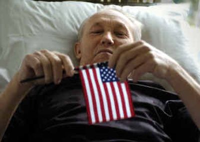 
Mikhail Zuyev, 73, raises his hand in his bedroom while becoming a U.S. citizen. 
 (Christopher Anderson/ / The Spokesman-Review)