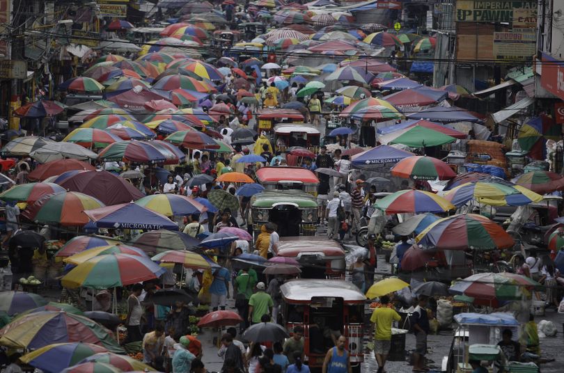 Passenger jeepneys make their way along a crowded public market as people and vendors cover themselves with umbrellas during a downfall in suburban Manila, Philippines on Wednesday June 8, 2011. Traffic snarled as the Philippine capital experienced a day of rain. (Aaron Favila / Associated Press)