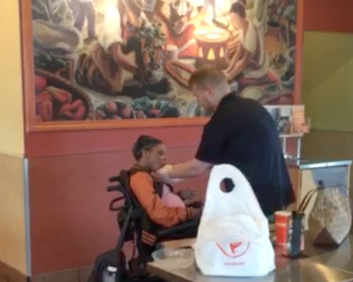 This image from a customer’s video shows worker Ridge Quarles feeding a disabled woman her food at the Qdoba restaurant in Louisville, Ky., on April 29. (Associated Press)