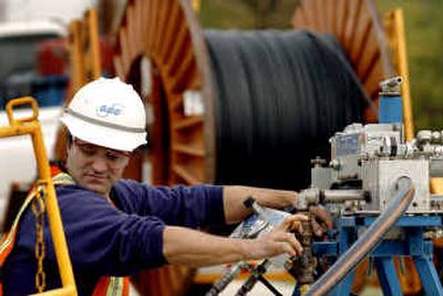 
A fiber crew member with SBC Communications, Inc., uses a machine to push fiber-optic cable into an underground conduit Friday in Illinois. 
 (Associated Press / The Spokesman-Review)