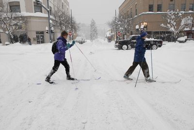 Jackie Beery, left, and Judy Waring ski across Fourth Street at Sherman Avenue in Coeur d’Alene on  Dec. 18 as snow  from the massive winter storm blanketed the region. Most adults seemed to forget how to have fun in the snow during December’s onslaught.  (Jesse Tinsley / The Spokesman-Review)