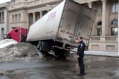 Spokane police Officer Mike McCasland waits for a tow truck to free a truck jackknifed on a snow berm this week at Riverside Avenue and Madison Street. (Colin Mulvany / The Spokesman-Review)