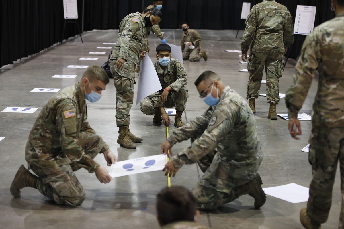 Members of the Nevada National Guard install social distancing stickers while setting up a new temporary coronavirus testing site Monday, Aug. 3, 2020, in Las Vegas.  (John Locher)