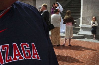 
Gonzaga windbreaker-clad Paul Turner, in search of Zag fans, walks among one of 33 wedding  parties Friday at the Salt Lake Temple. 
 (Brian Plonka / The Spokesman-Review)