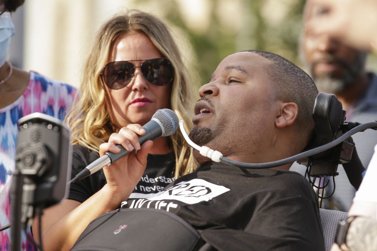 In this June 6, 2020 photo, Jerime Mitchell speaks to the crowd as his wife Bracken holds the microphone during a protest against police brutality at Greene Square in Cedar Rapids, Iowa. An insurance company for the City of Cedar Rapids will pay $8 million to Mitchell, who was paralyzed after police officer Lucas Jones shot him during a 2016 traffic stop.  (Jim Slosiarek)