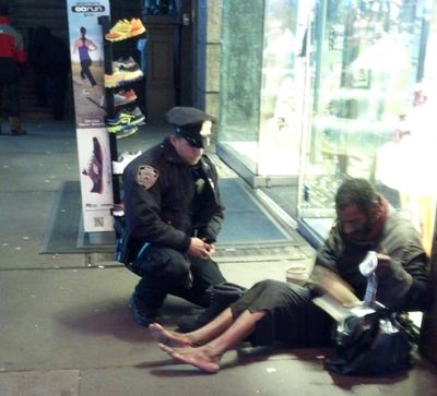 This photo provided by Jennifer Foster shows New York City Police Officer Larry DePrimo presenting a barefoot homeless man in New York's Time Square with boots Nov. 14, 2012 . Foster was visiting New York with her boyfriend on Nov. 14, when she came across the shoeless man asking for change in Times Square. As she was about to approach him, she said the officer  came up to the man with a pair of all-weather boots and thermal socks on the frigid night. She took the picture on her cellphone. It was posted Tuesday night to the NYPD's official Facebook page and became an instant hit. More than 350,000 users 