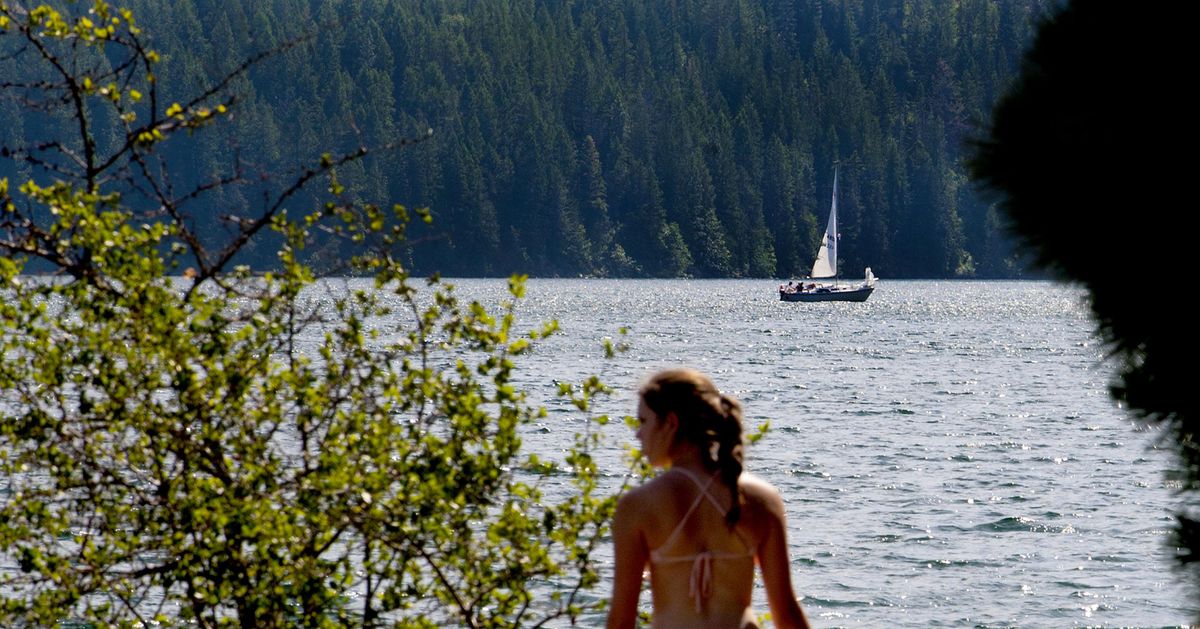 A sailboat cruises past a swimmer at Farragut State Park in Athol on Tuesday, June 23, 2015. (Kathy Plonka / The Spokesman-Review)