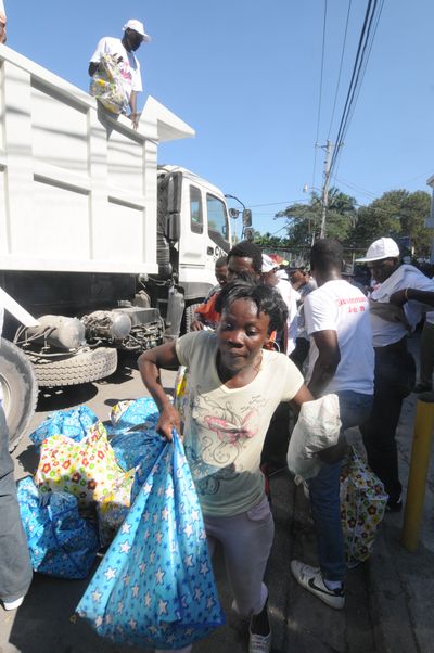 A Haitian woman carries a bag from a relief truck as they distribute food to the tent cities in downtown Port-au-Prince, Haiti, on Thursday.  (Associated Press)