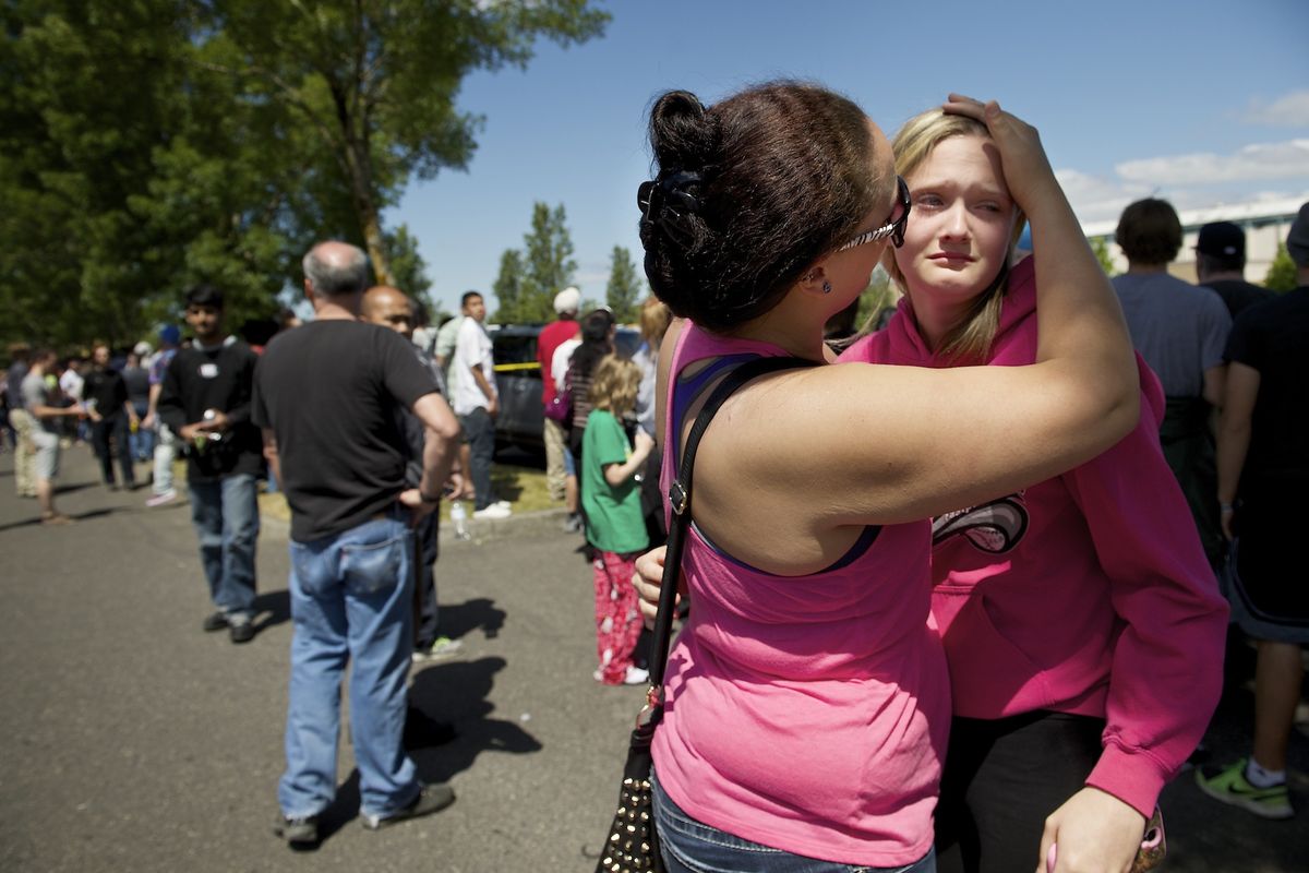 Briannah Wilson, 21, left, comforts her sister, Trisha, 15, as students reunite with family at a shopping center in Wood Village, Ore., after the shooting at Reynolds High School. (Associated Press)