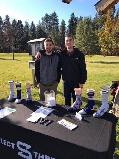 Select Threads co-owners Zach Stensland and Kyle Peterson stand behind a display showing samples of their company’s products last spring at a fundraising event. (Courtesy of Kyle Peterson)