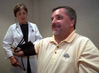 
Robert Reaghard, right, has his blood pressure checked by nurse Bunny Teeslink at Fieldale Farms, a small Georgia chicken company in Baldwin, Ga.  
 (Associated Press / The Spokesman-Review)