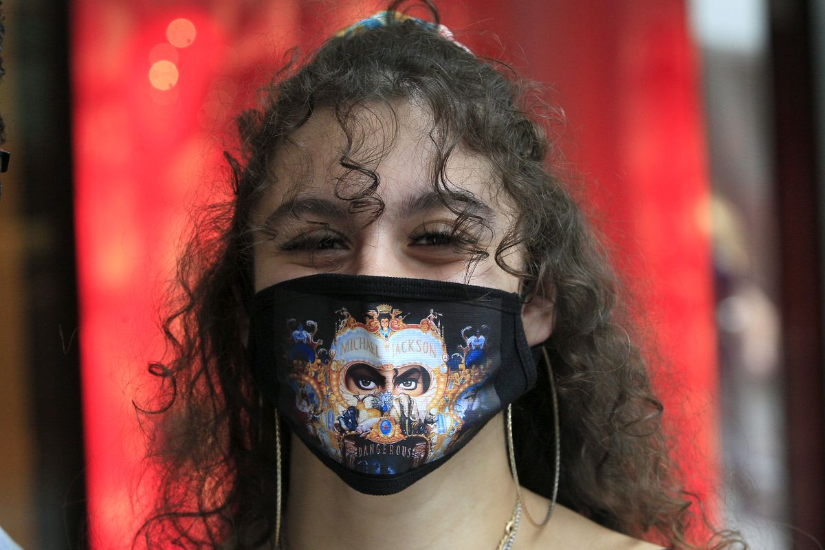 Singer Fallon Nicole, 23, left, wears a custom made "Michael Jackson" themed face mask, as she shops at the Louis Vuitton boutique at the opening of Beverly Center shopping mall in Los Angeles, Friday, May 29, 2020. According to a new poll, Americans overwhelmingly are in favor of requiring people to wear masks around other people outside their homes, reflecting fresh alarm over spiking infection rates. The poll also shows increasing disapproval of the federal government