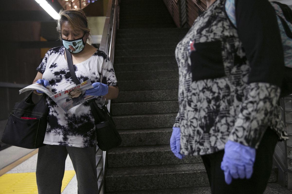 Women with face masks and protective gloves wait for a Metro Rail train on July 6 in Los Angeles during the coronavirus pandemic.  (Jae C. Hong)