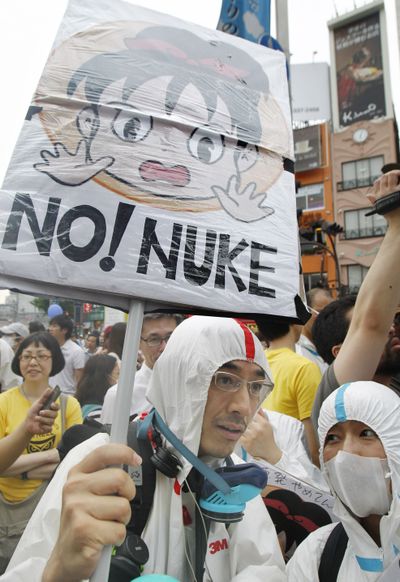 Anti-nuclear demonstrators wearing protective suits march down streets in Tokyo on Saturday. (Associated Press)