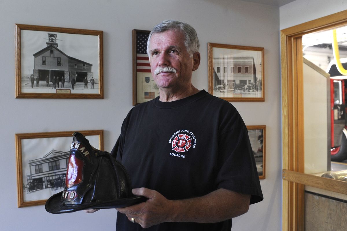 Spokane Fire Department Lt. Greg Borg holds a 1910 Spokane Fire helmet in the lobby of Fire Station No. 3 on Tuesday. Borg has compiled a list of firefighters who have died in the line of duty and is trying to raise funds to place plaques at the locations of their deaths. (Jesse Tinsley)