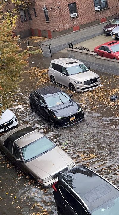 A person drives a car through a flooded street amid rains on Thursday in New York.  (Abigail Ekue/via REUTERS)