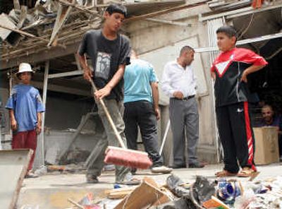 
Young men clean up debris from the site of a car bomb attack in east Baghdad that killed two people  and wounded six   Monday. Associated Press
 (Associated Press / The Spokesman-Review)