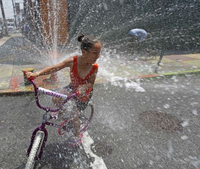 A child  cools off in spraying water from a fire hydrant in the Kensington neighborhood of Philadelphia on Tuesday.  (Associated Press)
