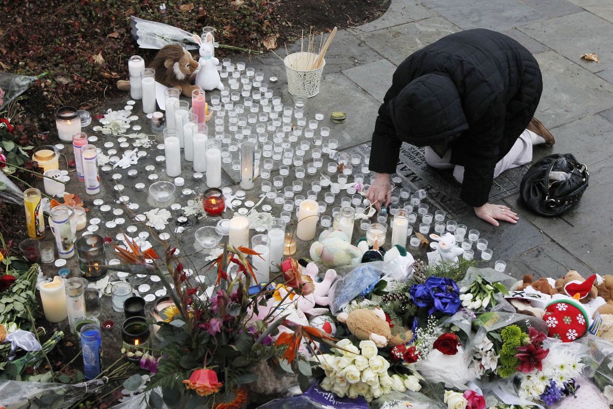 A woman pays respects at a memorial outside of St. Rose of Lima Roman Catholic Church, Sunday, Dec. 16, 2012, in Newtown, Conn. On Friday, a gunman allegedly killed his mother at their home and then opened fire inside the Sandy Hook Elementary School in Newtown, killing 26 people, including 20 children. (Julio Cortez / Associated Press)