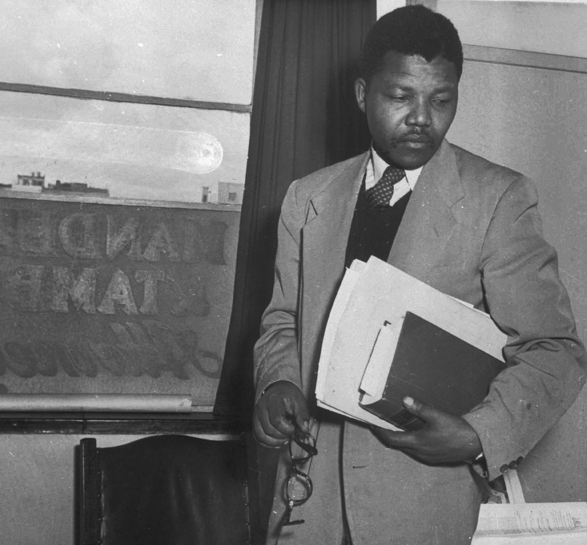 FILE- This is a 1952 file photo of ANC leader Nelson Mandela in the law office he opened with his colleague, Oliver Tambo. This was the first black legal practice in Johannesburg, South Africa. The names Mandela and Tambo can be seen written across the window pane. Nelson Mandela and his African National Congress are expected to be propelled into power when the final ballot is counted in South Africa