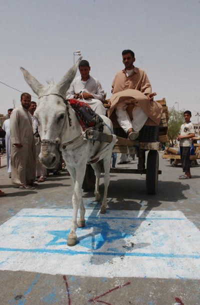 
Iraqis steer a donkey and cart over a representation of an Israeli flag during a protest Monday in Najaf denouncing Israel's attack Sunday on Lebanese civilians. 
 (Associated Press / The Spokesman-Review)