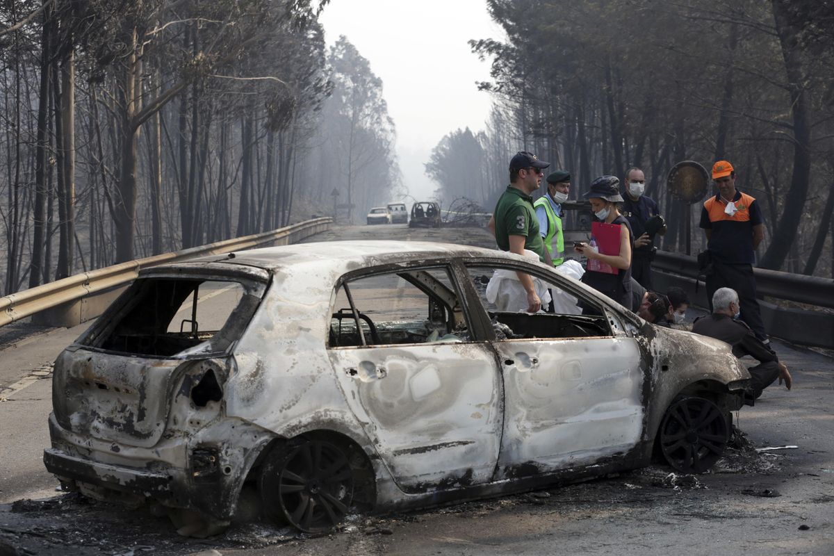 Police investigators stand by a burnt car on the road between Castanheira de Pera and Figueiro dos Vinhos, central Portugal, Sunday, June 18 2017. Raging forest fires in central Portugal killed more than 50 people, many of them trapped in their cars as flames swept over a road, in what the prime minister on Sunday called “the biggest tragedy of human life that we have known in years.” (Armando Franca / Associated Press)