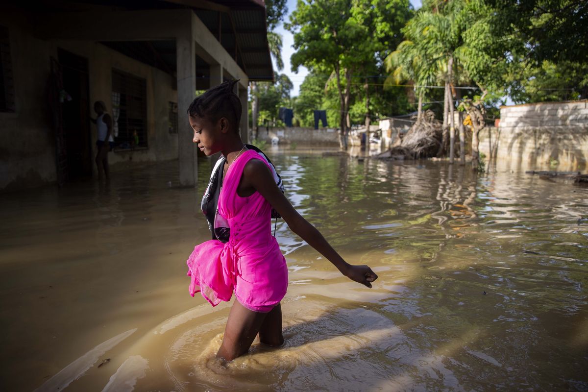 A girl wades towards her flooded home the day after the passing of Tropical Storm Laura in Port-au-Prince, Haiti, Monday, Aug. 24, 2020. Laura battered the Dominican Republic and Haiti on it