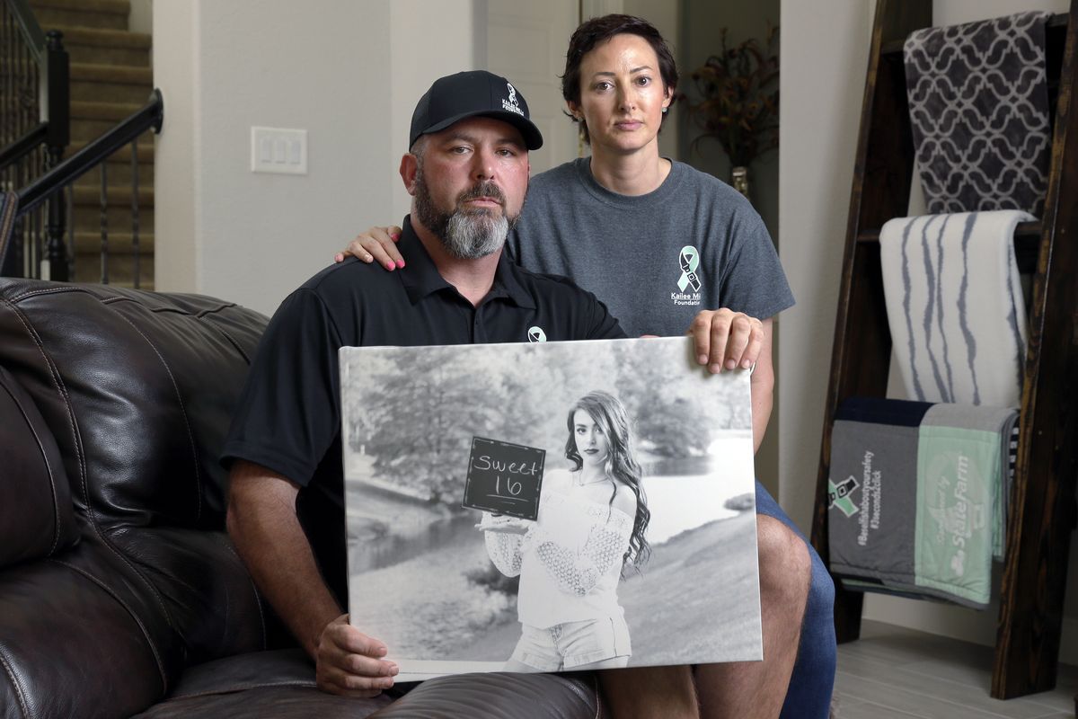 In this Oct. 12, 2021 photo, David and Wendy Mills, parents of Kailee Mills who was killed four years ago in an automobile accident when riding in the back seat without a seat belt, with a photo of their daughter at their home in Spring, Texas. The teenager was riding in the back seat of a car to a Halloween party in 2017 just a mile from her house when she unfastened her seat belt to slide next to her friend and take a selfie. Moments later, the driver veered off the road and the car flipped, ejecting her.  (Michael Wyke)
