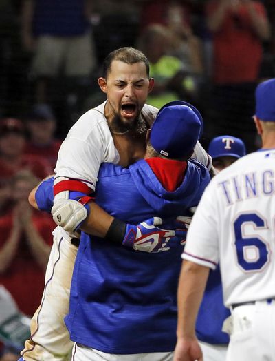 Texas’ Rougned Odor celebrates with manager Jeff Banister, bottom, after Odor hit a two-run homer in the bottom of the ninth inning to defeat Seattle on Tuesday. (Tony Gutierrez / Associated Press)