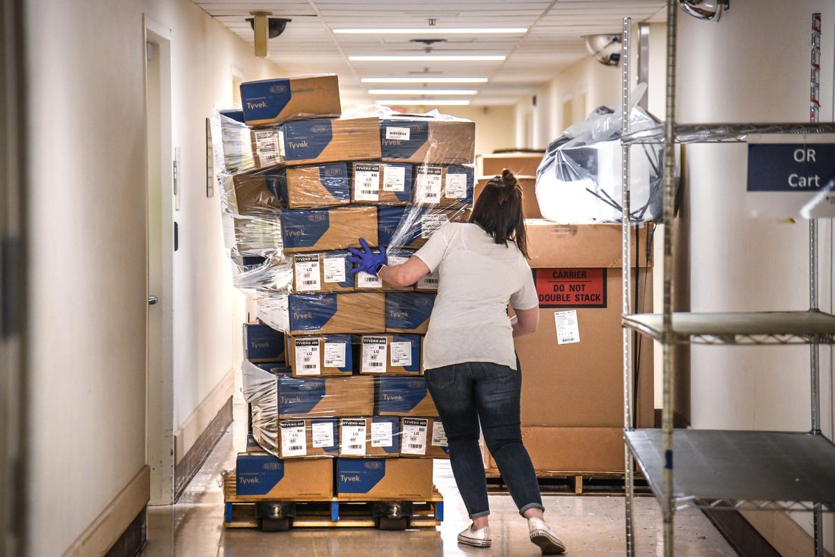 Bethany White, Providence Sacred Heart Medical Center supply chain manager, helps stabilize a shifting pallet of protective gowns as the third of five shipments of PPEs arrived at Sacred Heart from the state, Saturday, April 4, 2020. The shipment also included masks, gloves and hand sanitizer to help protect against COVID-19. (Dan Pelle / The Spokesman-Review)