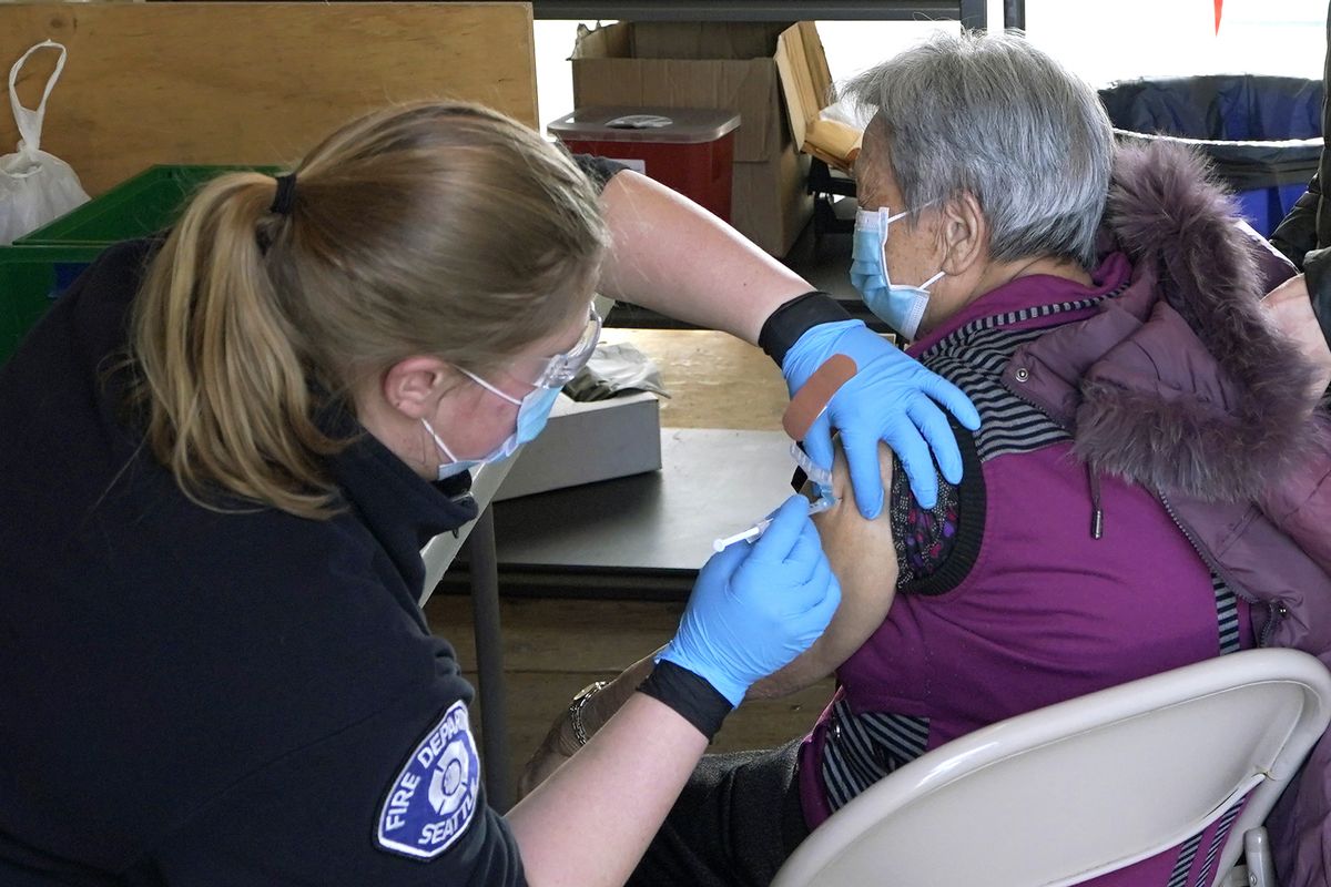 Kristin May, left, an EMT with the Seattle Fire Dept., gives the first dose of the Moderna COVID-19 vaccine to Nu Xiao Jiang, right, Monday, March 1, 2021, at a City of Seattle community COVID-19 testing and vaccination clinic in Seattle