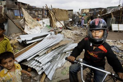 “Slumdog Millionaire” star Azharuddin Mohammed Ismail  rides past bulldozed homes  in his Mumbai, India, shantytown  Thursday.  (Associated Press / The Spokesman-Review)