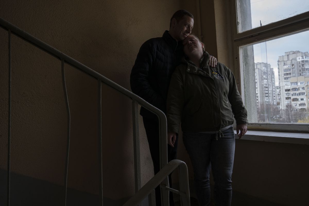 Iryna and Volodymyr, internally displaced from Irpin, lean on each other, on the stairwell near an apartment they took refuge in with four other adults from Irpin, in Lviv, western Ukraine, Sunday, April 3, 2022. Iryna and her husband Volodymyr were trapped for days between Ukrainian and Russian forces and quickly learned to distinguish between incoming and outgoing fire. They took shelter in a basement and whenever the shelling eased, they climbed out to shout to their neighbors to see if they were still alive. (Nariman El-Mofty)